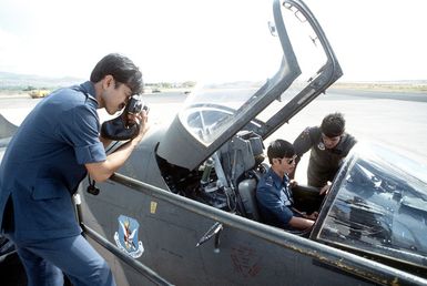 MAJ Lance Smith of the 23rd Tactical Fighter Wing Flying Tigers explains to Flight LT. Goh Chyelee of the Royal Singapore Air Force, cockpit features of an A-7D Corsair II aircraft during their participation in a joint exercise. Flight LT. Tom Wong of the Royal Singapore Air Force takes a photograph of the demonstration