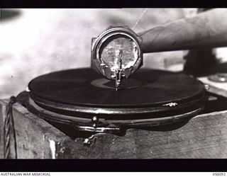 EDIE CREEK, NEW GUINEA. 1943-08-15. THE DIAPHRAGM FOR THIS HOME-MADE GRAMOPHONE WAS MADE FROM A TOBACCO TIN