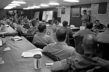 Navy and Marine officers receive an operational status briefing in the wardroom aboard the amphibious assault ship USS SAIPAN (LHA 2). The SAIPAN is on station off the coast of Liberia for Operation Sharp Edge