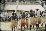 Dancers in grass skirts and matching headress; some with western dress or tops