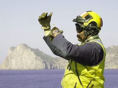 Aviation Boatswains Mate Handler 1ST Class James PETTY directs an aircraft during Exercise DYNAMIC MIX off the coast of Capo Teulada, Sardinia, Italiy, onboard the Landing Helicopter Assault Ship (LHA 2) USS SAIPAN