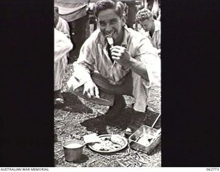 RAMU VALLEY, NEW GUINEA. 1943-12-25. VX79823 TROOPER R. H. GRIFFITHS (1) A PATIENT OF THE 2/6TH FIELD AMBULANCE ENJOYING HIS CHRISTMAS DINNER