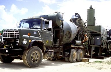 A Seabee of Naval Mobile Cosntruction Battalion 1 (NMCB-1) stands beside a concrete mixer