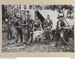 DAGUA AREA, NEW GUINEA. 1945-04-04. 2/3INFANTRY BATTALION TROOPS OUTSIDE "MAC'S HALF-WAY HOUSE", A YMCA HUT SUPPLIED BY AUSTRALIAN COMFORTS FUND, WHERE TEA AND LEMON DRINKS ARE POURED DOWN THIRSTY ..