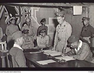 TOROKINA, BOUGAINVILLE. 1945-09-08. VICE-ADMIRAL BARON SAMEJIMA, IMPERIAL JAPANESE NAVY, SIGNING THE INSTRUMENT OF SURRENDER DURING A FORMAL SURRENDER CEREMONY AT HQ 2 CORPS. THE SURRENDER WAS ..