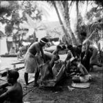 Men sewing together sections of a canoe