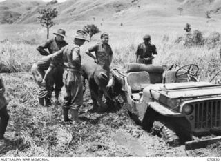 KESAWAI, RAMU VALLEY, NEW GUINEA, 1944-03-05. MEMBERS OF THE 2/12TH INFANTRY BATTALION ATTEMPTING TO MOVE A JEEP BOGGED IN THICK MUD NEAR KESAWAI. THE SLIGHTEST RAIN MAKES THESE TRACKS USELESS FOR ..