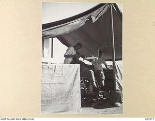 CAPE WOM, WEWAK AREA, NEW GUINEA. 1945-09-01. CAPTAIN V.J. TAYLOR, SECOND IN COMMAND 2/4 DENTAL UNIT ATTACHED HEADQUARTERS 6 DIVISION AT WORK IN HEADQUARTERS SURGERY