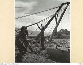 EVAPIA RIVER, NEW GUINEA, 1944-03-15. THE HUGE MAIN SUPPORT FOR THE SUSPENSION BRIDGE UNDER CONSTRUCTION OVER THE EVAPIA RIVER NEAR KESAWAI, BEING HOISTED INTO POSITION BY ENGINEERS FROM THE 2/4TH ..