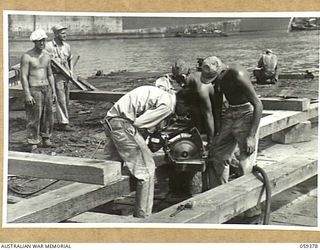 LAE, NEW GUINEA, 1943-11-05. TROOPS OF THE 1052ND ENGINEERS PORT CONSTRUCTION AND REPAIR GROUP, UNITED STATES ARMY USING A PORTABLE AIR DRIVEN SAW DURING THE CONSTRUCTION OF THE FIRST LIBERTY DOCK