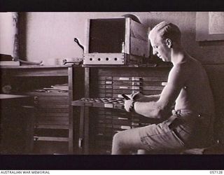 SEVENTEEN MILE, NEW GUINEA. 1943-09-23. VX142290 SAPPER J. R. LINEY OF THE 2/1ST AUSTRALIAN ARMY TOPOGRAPHICAL SURVEY COMPANY SETTING UP TYPE FOR MAP PRINTING