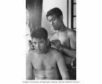 RAN-ANNIM crewman Alexander Lelen cutting William Allen's hair, Bikini Atoll, summer 1964