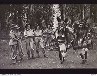 DOBODURA, NEW GUINEA. 1943-10-10. FIVE AUSTRALIAN NURSING SISTERS WATCHING TWO NATIVES DOING A CEREMONIAL DANCE