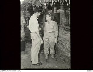 VIVIGANI, GOODENOUGH ISLAND, PAPUA. C. 1944-02-21. MISS BERT HENDRIE OF NEW YORK AND 58776 CORPORAL J. ROBERTSON RAAF OF MELBOURNE, VIC, CHAT OUTSIDE THE AMERICAN RED CROSS CANTEEN ADJACENT TO THE ..