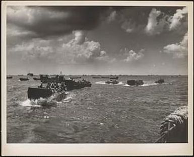 Swarms of coast guard-manned landing craft carry in marine and army troops to the shores of Saipan