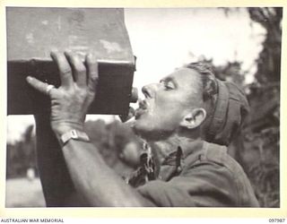 WEWAK AREA, NEW GUINEA. 1945-10-13. PRIVATE W. MUMFORD, 3 MOBILE TYRE WORKSHOP SECTION, DRINKING FROM A WATER CAN
