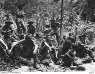 FARIA VALLEY, NEW GUINEA. 1944-01-11. PERSONNEL OF B COMPANY, 2/9TH INFANTRY BATTALION ENGAGED IN ARMED ESCORT DUTIES FOR THE NATIVE CARRIERS TAKING SUPPLIES TO THEIR UNIT, PAUSE FOR A SMOKE BEFORE ..