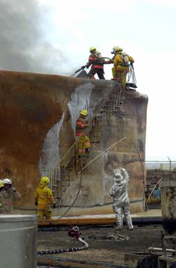 US Air Force (USAF) MASTER Sergeant (MSGT) Kenneth Reeves from the 36th Civil Engineer Squadron (CES), Fire Protection Flight stationed at Andersen Air Force Base (AFB), Guam works with members of the Guam Fire Department to extinguish a fuel tank fire on the Cabras Island tank farm