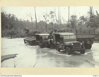 LAE-NADZAB, NEW GUINEA. 1944-07-19. PERSONNEL OF THE MILITARY HISTORY SECTION PREPARING TO USE THEIR HEAVY TRUCK TO HAUL A JEEP AND TRAILER OUT OF A BADLY FLOODED SECTION OF THE LAE-NADZAB ROAD. ..