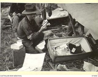 MADANG, NEW GUINEA. 1944-04-25. NX102131 STAFF SERGEANT G.L. RICH, Z FIELD SECURITY SECTION, ATTACHED TO 5TH DIVISION, EXAMINES CAPTURED JAPANESE DOCUMENTS