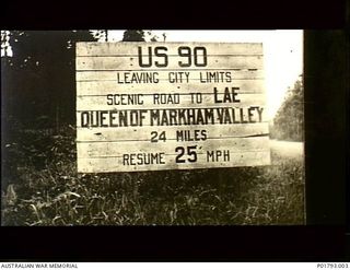 Nadzab, New Guinea. c.1944. Sign on the road to Lae which reads `US 90 Leaving city limits Scenic road to Lae Queen of Markham Valley 24 miles Resume 25 mph'. (Original housed in AWM Archive Store)