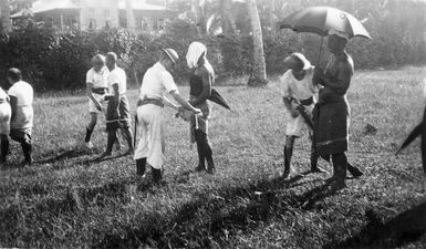 Sailors removing the white band, the insignia of the Mau, from lava lavas