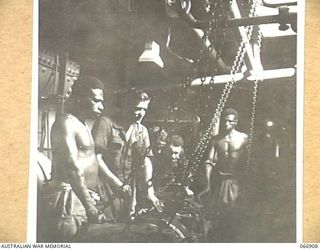 NEW GUINEA. 1944-06-15. NX23747 LIEUTENANT E.N.T. BEST, CHIEF ENGINEER OF THE AB442 A VESSEL OF THE 12TH WATER TRANSPORT OPERATING COMPANY, SUPERVISING AN OVERHAUL OF ONE OF THE SHIPS ENGINES