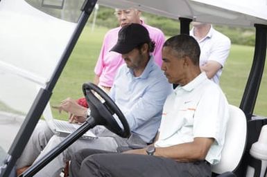 Barack Obama confers with Robert Baker after he plays golf in Kaneohe Bay, Hawaii, December 24, 2014