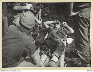 BOUGAINVILLE. 1945-04-26. TPR C. PARKER, 2/4 ARMOURED REGIMENT (1), SHOT THROUGH THE LEG DURING 24 INFANTRY BATTALION'S ADVANCE ALONG BUIN ROAD SOUTH OF SINDOU RIVER, RECEIVING TREATMENT