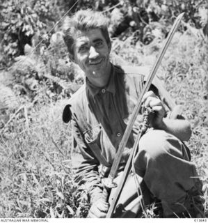 1942-11-23. New Guinea. Kokoda Track. Sergeant W. R. Edmonds of N.S.W. displays a Japanese officer's sword. The handle is covered with shark skin which glistens when the light catches the raised ..