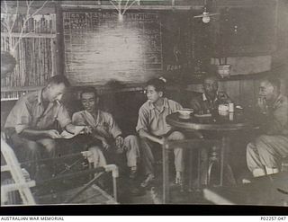 Lesson Point, Rabaul, New Britain, 1945-10. After the Japanese surrender at the end of the war, members of a RAAF Equipment Recovery Party sit and smoke cigarettes with Japanese servicemen in the ..