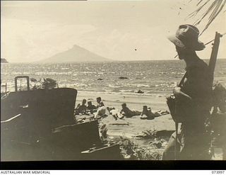 DUGUMUR BAY, NEW GUINEA. 1944-06-14. MEMBERS OF 4TH INFANTRY BATTALION SUNBAKING ON THE BEACH UNDER THE GUARD OF A SENTRY, AT A TWO POUNDER ANTI-TANK GUN SITED FOR BEACH DEFENCE AGAINST BARGE ..