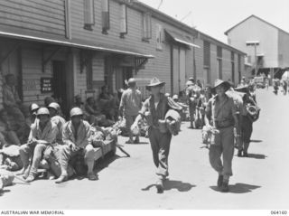 TOWNSVILLE, QLD. 1944-01-28. PERSONNEL OF THE 2/28TH INFANTRY BATTALION, MOVING ALONG THE WHARF TO THEIR TRAIN ON THEIR RETURN HOME FROM NEW GUINEA, PASSING UNITED STATES COLOURED (NEGRO) SOLDIERS ..