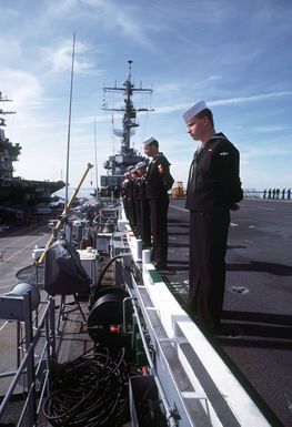 Sailors man the rails aboard the amphibious assault ship USS GUAM (LPH-9) as the vessel prepares to depart from port