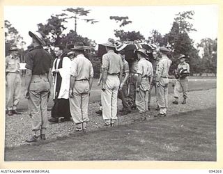 LAE AREA, NEW GUINEA. 1945-07-23. PALL BEARERS CARRYING THE REMAINS OF PRIVATE B.J. SMITH THROUGH A GUARD OF HONOUR COMPRISING FRIENDS OF THE DECEASED, DURING A FUNERAL SERVICE CONDUCTED AT LAE WAR ..