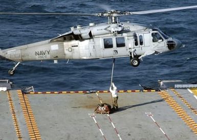 US Navy (USN) flight deck personnel attach a cargo pendant to an MH-60S Seahawk helicopter on the flight deck of the Amphibious Assault Ship USS SAIPAN (LHA 2)