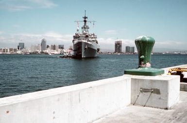 A commercial harbor tug maneuvers the miscellaneous flagship USS CORONADO (AGF-11) into port at Naval Air Station, North Island, San Diego. The CORONADO, flagship for Commander, Third Fleet, will be arriving at its new home port after being stationed in Hawaii for almost 20 years