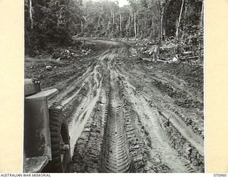 ZENAG, NEW GUINEA, 1944-02-27. AN EXPERIMENTAL SECTION OF THE ROAD FIFTY EIGHT TO FIFTY EIGHT AND A HALF MILES FROM WAU. THE CLAY SEAL OVER THE SWAMPY BLACK MUD IS PROVING SATISFACTORY, EVEN AFTER ..