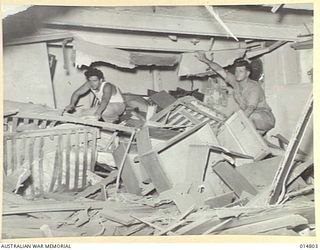 1943-05-07. NEW GUINEA. MILNE BAY. AN ALLIED VESSEL HIT DURING 1943-04-14, JAPANESE RAID ON MILNE BAY. R. TAYLOR OF SYDNEY AND E. CAESAR OF FREMANTLE, W.A. IN ONE OF THE WRECKED CABINS. (NEGATIVE ..