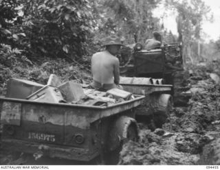 SOUTH BOUGAINVILLE. 1945-07-29. A TRACTOR TOWING TWO JEEP TRAILERS LOADED WITH STORES THROUGH HEAVY MUD ON THE BUIN ROAD IN 2 FIELD REGIMENT, ROYAL AUSTRALIAN ARMY. THE ROAD, OUR MAIN SUPPLY ROUTE, ..