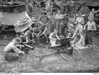 LAE, NEW GUINEA. 1944-10-27. PERSONNEL OF THE MACHINE GUN PLATOON, HEADQUARTERS COMPANY, 14/32ND INFANTRY BATTALION CLEANING UP THEIR VICKERS GUN WHILE AWAITING ORDERS TO EMBARK. IDENTIFIED ..