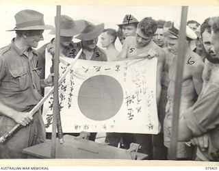 POTSDAM, NEW GUINEA. 1944-08-21. TROOPS OF THE 30TH INFANTRY BATTALION, WHO HAVE JUST RETURNED FROM THE FORWARD AREA NEAR THE SEPIK RIVER SHOWING TROPHIES CAPTURED FROM THE JAPANESE, TO MEMBERS OF ..