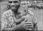 A New Caledonian missionary carrying in his arms the son of a leader of the New Hebrides