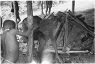 Woman, man and child and man making a leaf oven