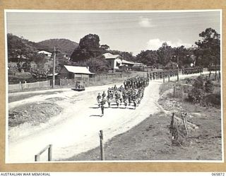 HERBERTON, QLD. 1944-04-25. PERSONNEL OF HEADQUARTERS, 6TH DIVISION, LED BY THE BAND OF THE 2/2ND INFANTRY BATTALION, MARCHING ALONG THE MAIN STREET TO THE WAR MEMORIAL TO TAKE PART IN THE ANZAC ..