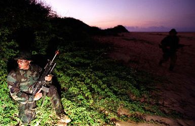 A Marine with the 11th Marine Expeditionary Unit from Camp Pendleton, California, armed with an M16A2 rifle prepares to conduct an early morning boat raid as a pre-emptive strike against enemy forces before a large amphibious assault by the 11th MEU slated for later in the day at Pacific Missle Range Facility, Barking Sands, Kauai, Hawaii, during RIMPAC 96. The amphibious assault involved Navy and Marine air, ground and sea forces for training as a combined amphibious assault force