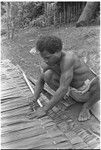 Man sewing thatch panel