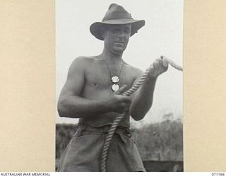 EVAPIA RIVER, NEW GUINEA, 1944-03-15. VX80468 SAPPER A.D. ISSEPP OF NO.1 PLATOON, 2/4TH FIELD COMPANY, ROYAL AUSTRALIAN ENGINEERS, STRIKING TROUBLE WITH THE HOIST ROPES AS HE HELPS PREPARE A LIFT ..