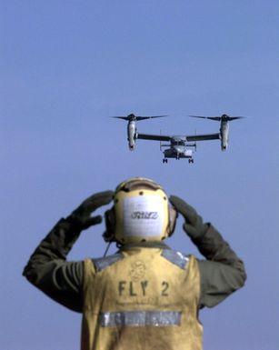 A Landing Signal Enlisted (LSE) Aviation Boatswain's Mate (BM) visually guides an MV-22B Osprey in for a landing aboard the USS SAIPAN (LHA 2)