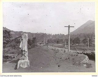 RABAUL, NEW BRITAIN. 1945-11-20. BROKEN STATUE OF CHRIST, ALL THAT IS LEFT OF THE RABAUL ROMAN CATHOLIC CHURCH IN MALAGUNA ROAD. A JAPANESE PILLBOX SURROUNDS THE STATUE